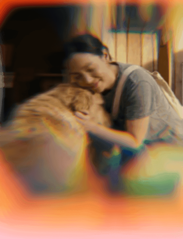 A young woman with dark hair lovingly hugs a fluffy light brown dog.